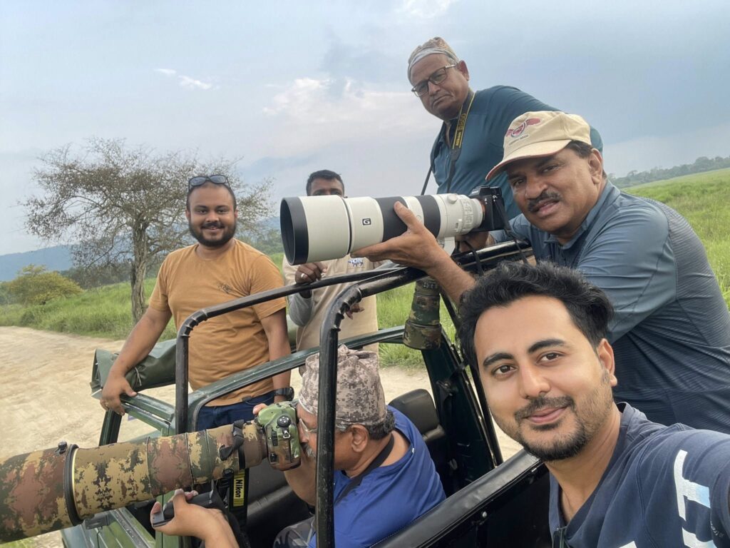 Group of photography enthusiasts with professional camera equipment and telephoto lenses on safari vehicle.